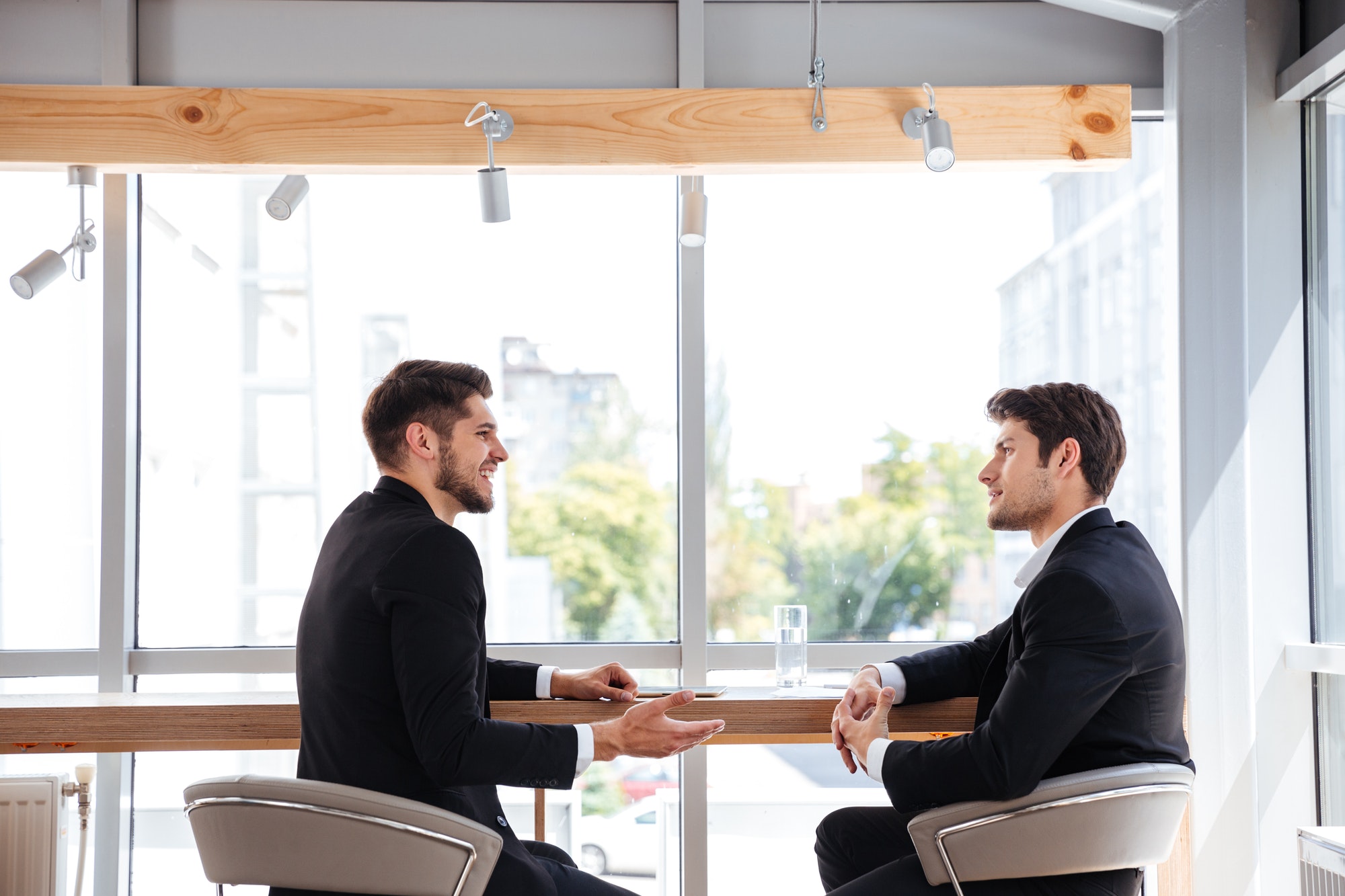Two cheerful young businessmen having business meeting